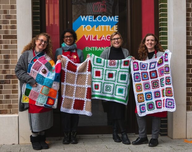 women from community group holding crochet blankets made for children living in poverty