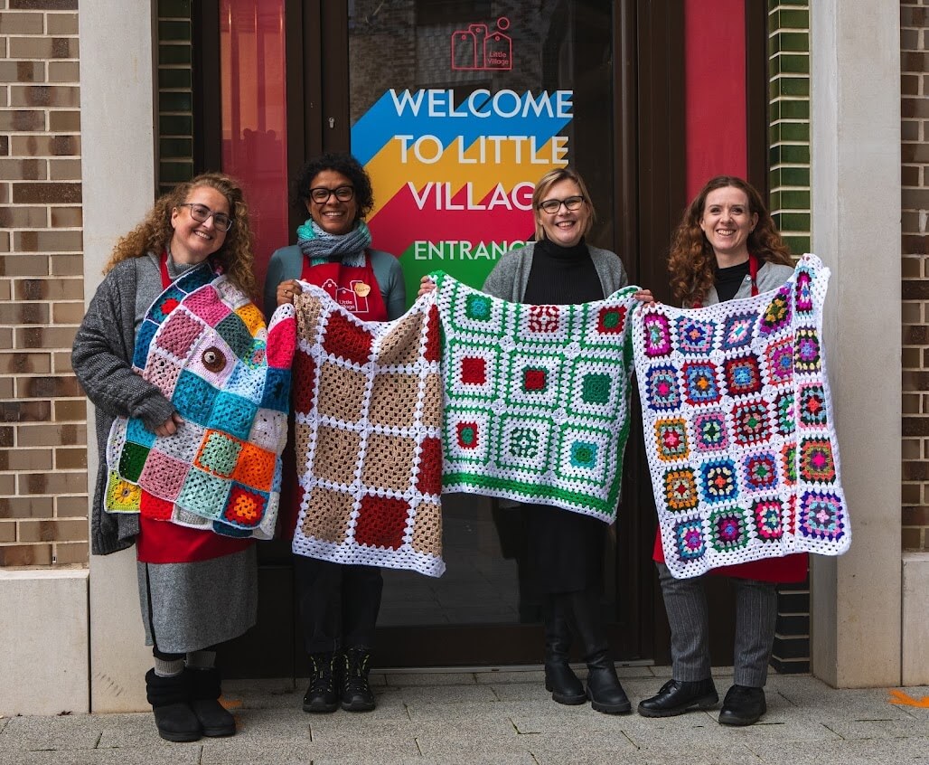 women from community group holding crochet blankets made for children living in poverty