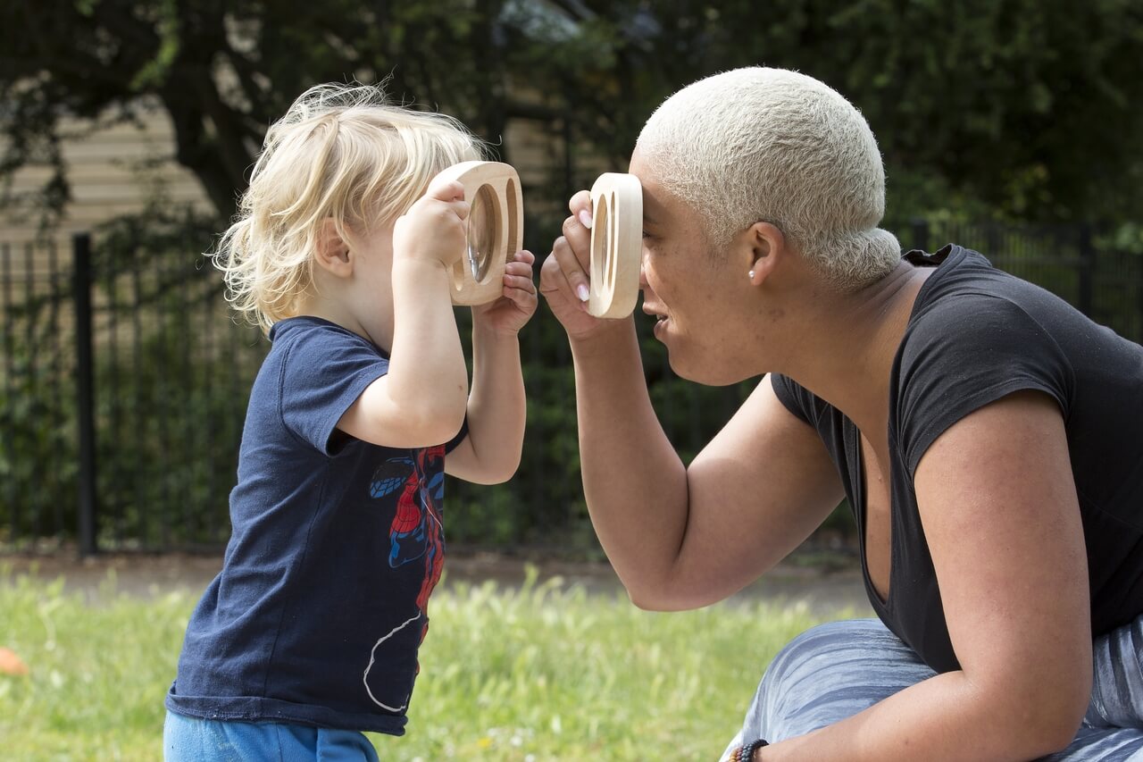 woman and toddler looking through magnifying glasses outdoors