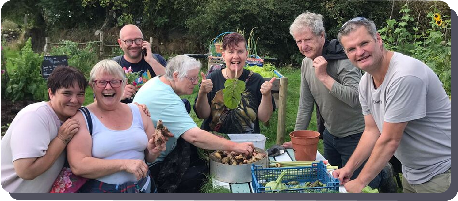 A group of people around a table in a community garden smiling
