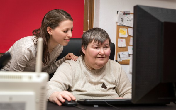 Charity helping someone working on a computer