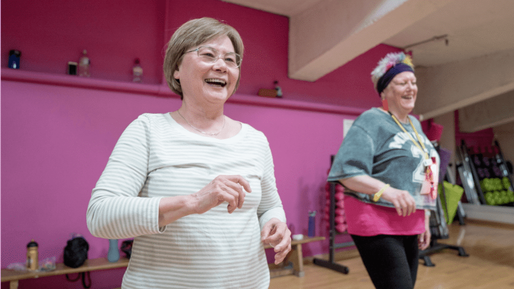 Two smiling older women laughing together during a group exercise class